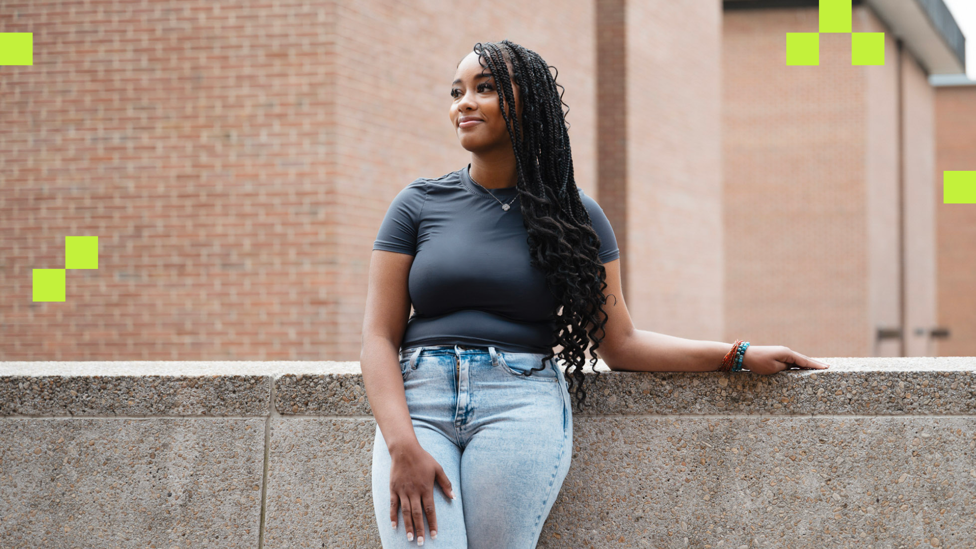 A young black woman leaning against a brick wall.