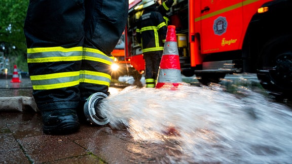 Wasser läuft aus dem Schlauch an einer Feuerwehrpumpe.
