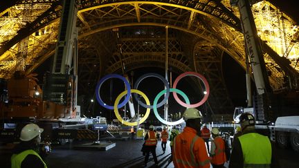 Des ouvriers regardent des grues retirer les anneaux olympiques de la Tour Eiffel à Paris, le 27 septembre 2024. (GEOFFROY VAN DER HASSELT / AFP)