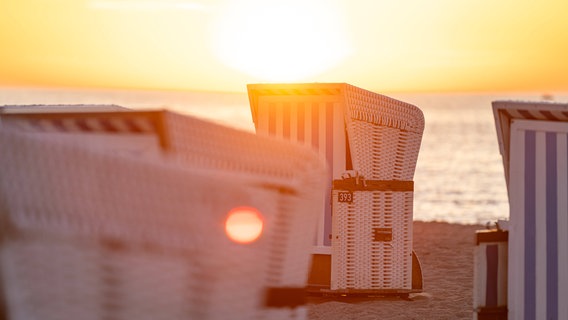 Strandkörbe am Strand bei untergehender Sonne. © Imago Images / Fotostand 