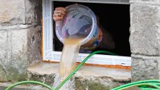 Symbolbild:Eine Person schüttet Wasser aus einem Eimer aus einem Kellerfenster.(Quelle:dpa/R.Pfeil)