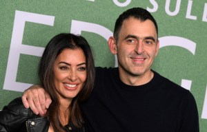 a man and woman are posing for a picture in front of a green background with the letter e on it