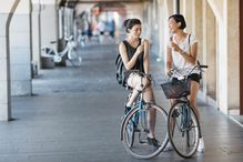 Two young women with bicycles eating icecream