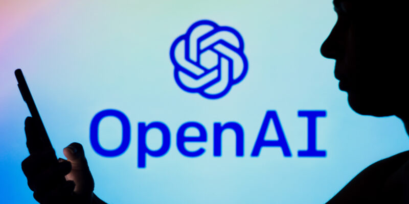 Het OpenAI logo met een silhouette van iemand met een smartphone op de voorgrond.