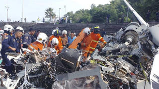 In this photo released by Fire & Rescue Department of Malaysia, fire and rescue department inspect the crash site of two helicopter in Lumur, Perak state, Monday, April 23, 2024. Malaysia's navy says two military helicopters collided and crashed during a training session, killing all 10 people on board. (Terence Tan/Ministry of Communications and Information via AP)
