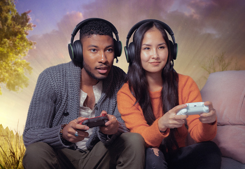 Two people wearing headsets playing Xbox games on a couch together