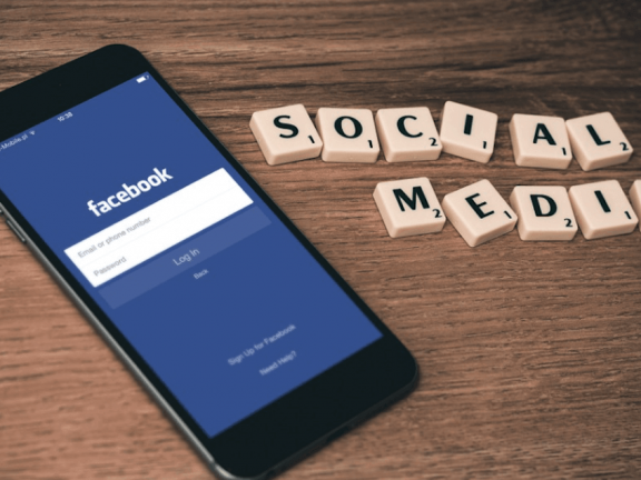Facebook op een mobiele telefoon, met daarnaast de letters 'SOCIAL MEDIA'