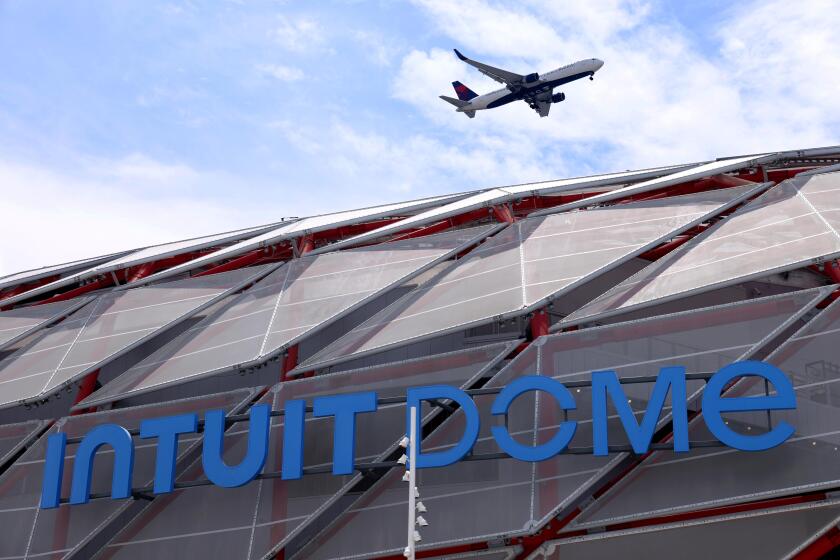 INGLEWOOD, CA - AUGUST 1, 2024 - A plane passes over the Intuit Dome Plaza in Inglewood on August 1, 2024. The sports stadium is still under construction. (Genaro Molina/Los Angeles Times)