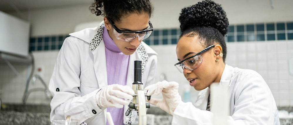 Two scientists working with a microscope in a laboratory.