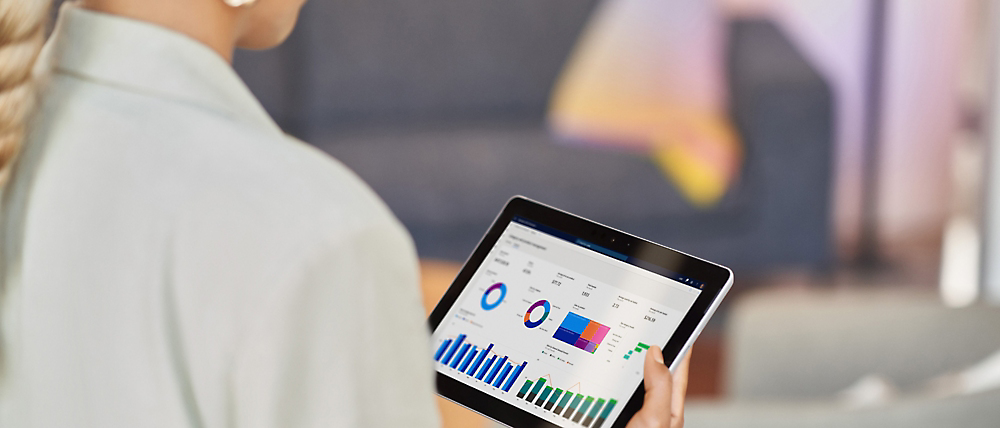 Eine Person, die ein Tablet mit farbigen Grafiken und Diagrammen hält, die Datenanalysen oder Geschäftsmetriken zeigen.