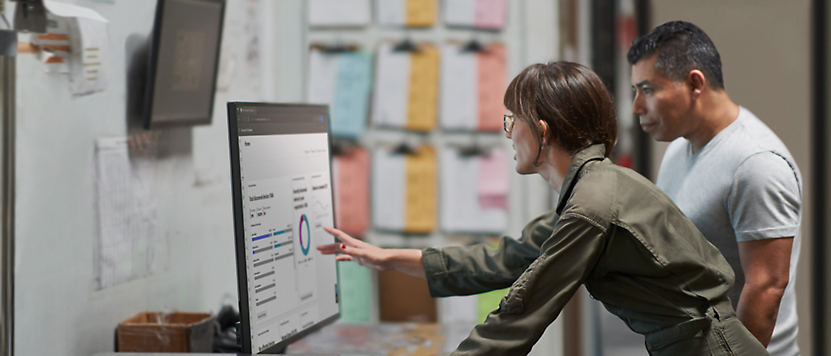 A person is showing a data chart on a computer to another person