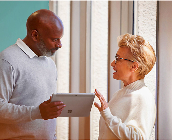 Two persons are discussing while on of them is holding a tablet