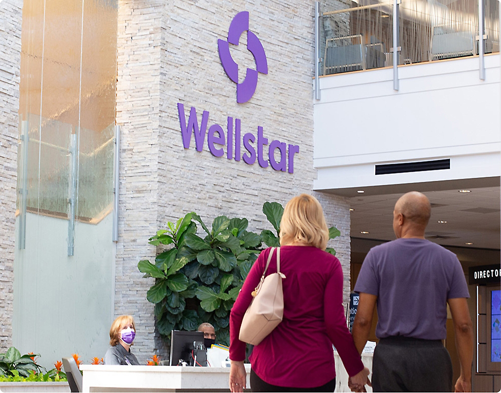 Zwei Personen gehen vor der Rezeption von Wellstar
