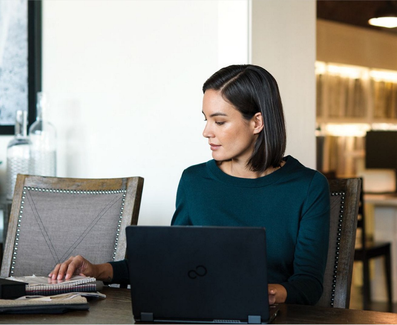 A woman working on her laptop and also notebooks placed on her table