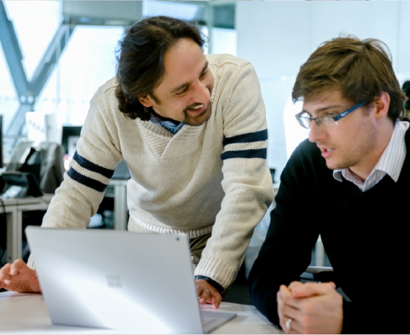 Two person in the office looking at a laptop and having a discussion