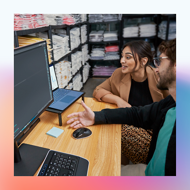 Two people discussing code on a computer screen in an office environment.