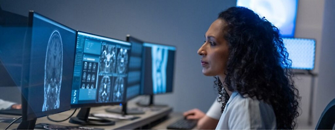 A woman watching multiple computer screens with data