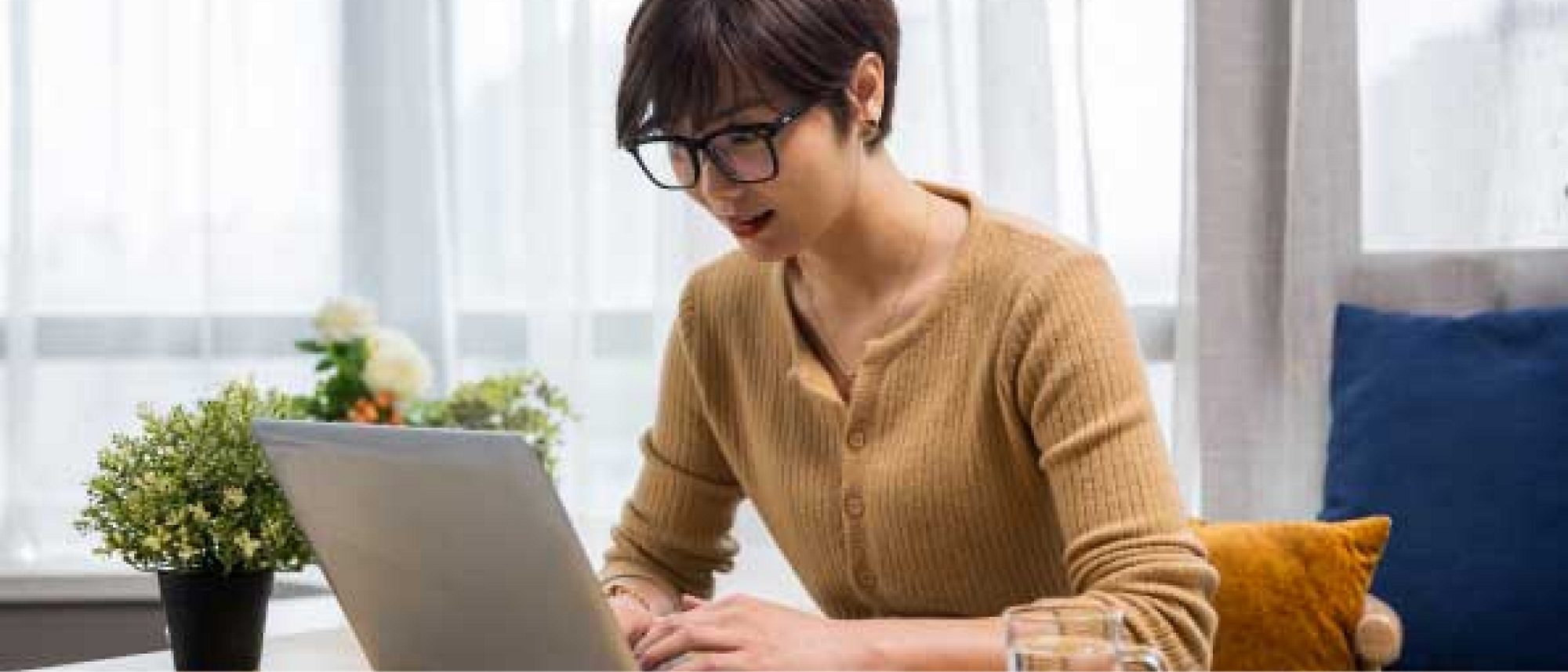 A woman is sitting at a table using a laptop.