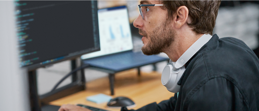 Focused male professional analyzing data on dual computer monitors.