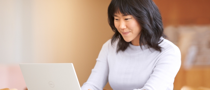 A woman is smiling and working on her laptop