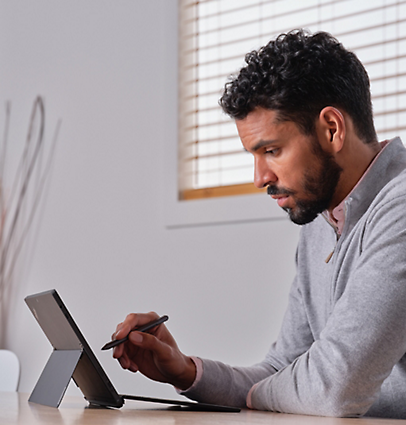 A person using a tablet, pen and keyboard.