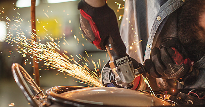 A person using a grinding wheel on a piece of metal.