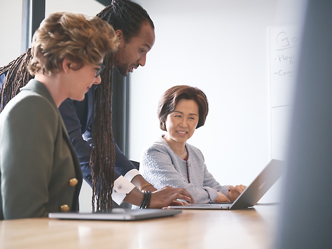 Three business people looking at a laptop.