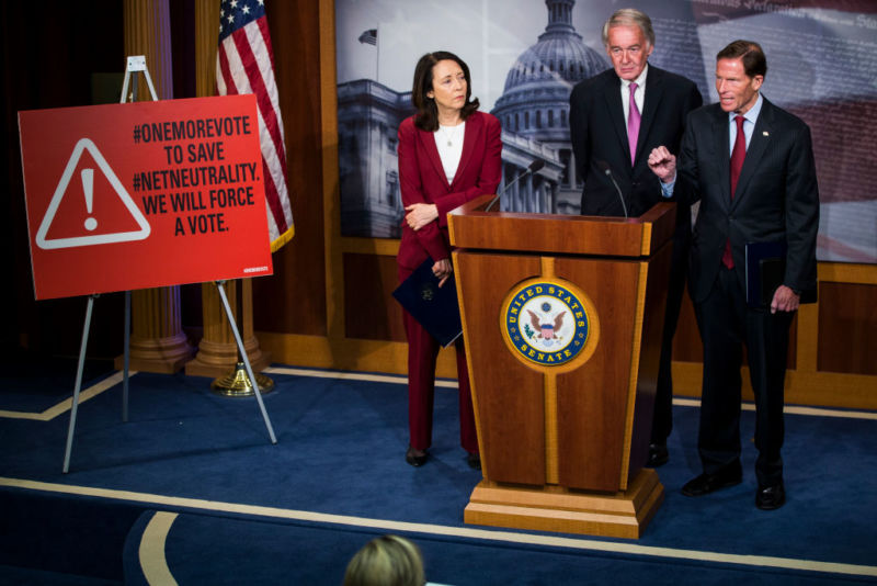 Three Democratic senators speaking next to a sign that says, 
