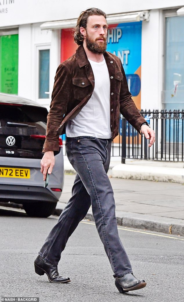 Aaron, 33, cut a casual figure with blue jeans which he paired with a white T-shirt and a brown suede jacket
