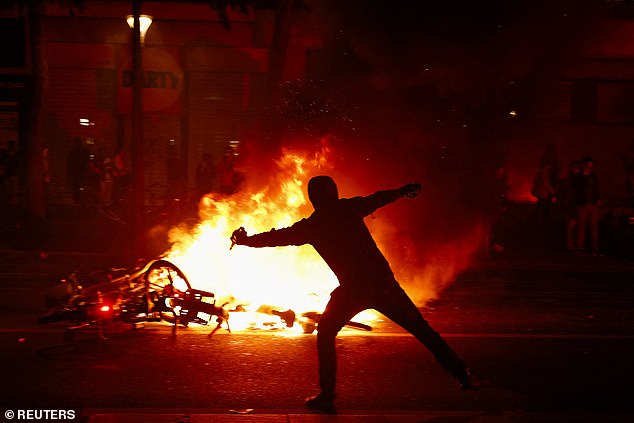PARIS: A protester throws a projectile near burning bicycles during clashes with police after the exit polls