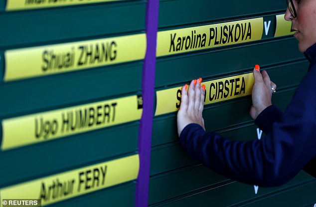 Staff prepare the order of play board before the start of play at Wimbledon this morning
