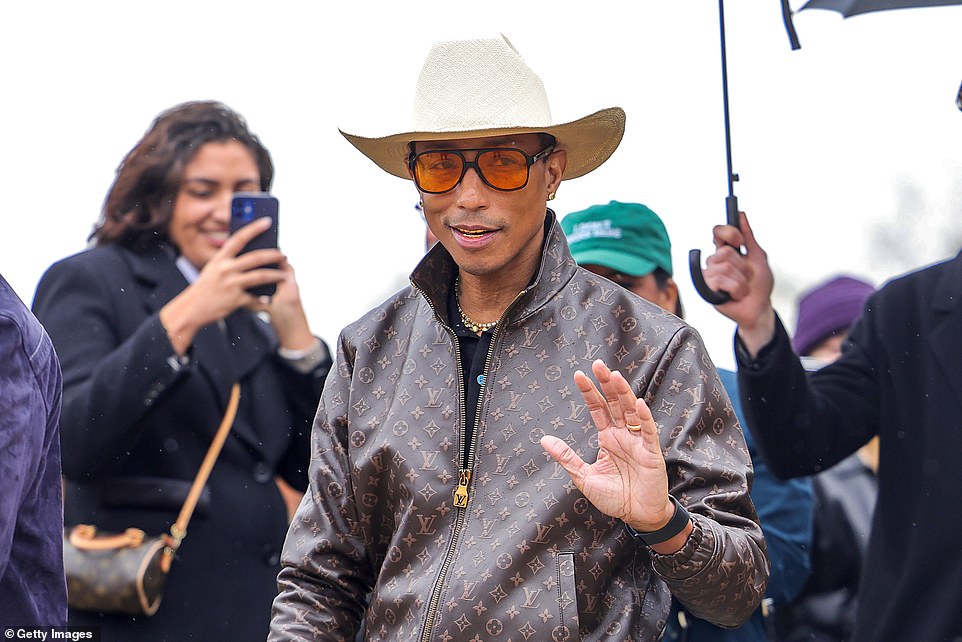 He opted for some orange-lensed glasses as he unzipped the jacket to reveal a black polo top