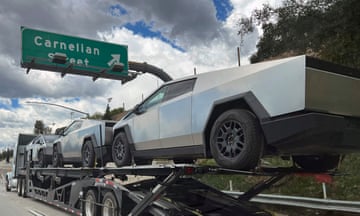 A transport vehicle carries three Tesla Cybertrucks on a freeway in California