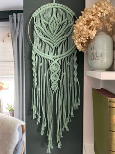 there is a green macrame hanging on the wall next to a book shelf