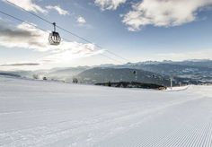 a ski lift is above the snow covered ground and hills in the distance are seen