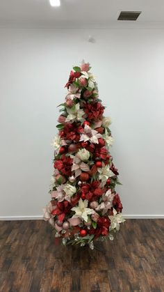 a woman is decorating a christmas tree with red, white and green flowers on it