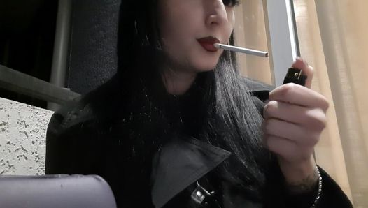 Dominatrice nika fume une cigarette sur le balcon. Les lèvres rouges sexy de la maîtresse te soufflent au visage