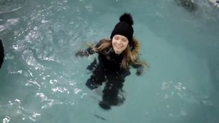 Wetlook-Mädchen mit Winterkleidung schwimmt im Pool
