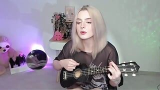 Heißes blondes Mädchen, das auf Ukulele spielt und in ungezogenem Outfit singt