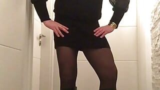 Nicki-crossdress in einem sexy schwarzen Minikleid, strumpfhose und stiefeln