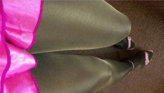 Tanned and black pantyhose layered legs satin pink miniskirt and heeled pink sandals.