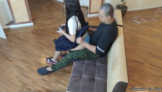 Mädchen spielt Videospiele, sitzt auf den Beinen eines alten Perversen, der ihre Unschuld ausnutzt