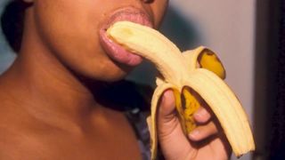 Safada ébano com lábios sensuais brincando com uma banana