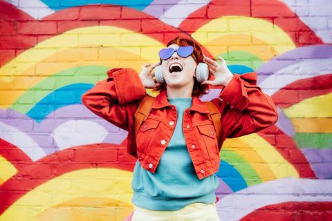 Gut gelaunte Frau vor einem Regenbogenhintergrund