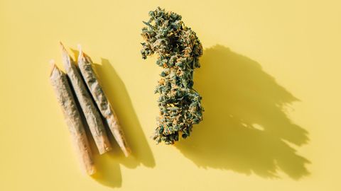 Drei gedrehte Joints liegen neben einer dicken Cannabis-Blüte
