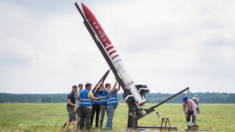 Eine Gruppe Männer stellt eine Rakete aufrecht