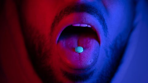 Nahaufnahme des Mundes des Mannes, der Ecstasy-Drogen schluckt (Symbolbild)