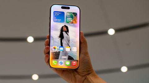 Ein iPhone 16 wird in Cupertino bei der Vorstellung nach oben gehalten. Der Homescreen zeigt iOS 18