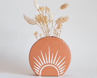 BaseRoots brand orange printed ceramic vase with dried flower arrangement.