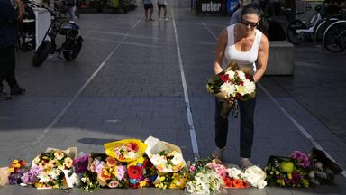 Eine Frau legt Blumen am Bondi Junction in Sydney ab